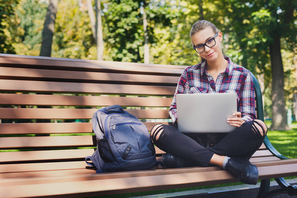 Young woman using laptop in park, copy space - Foto, Bild