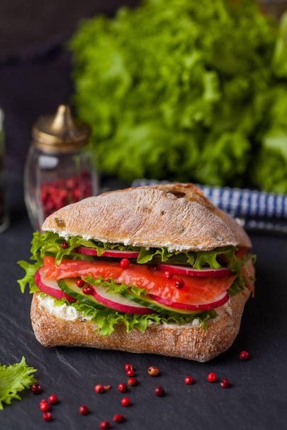 Ciabatta sandwich with salmon, vegetables and fresh salad on woo - Фото, изображение