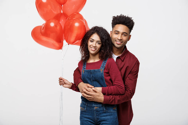 Close up attractive African American couple huging and holding red heart balloon. - Фото, изображение