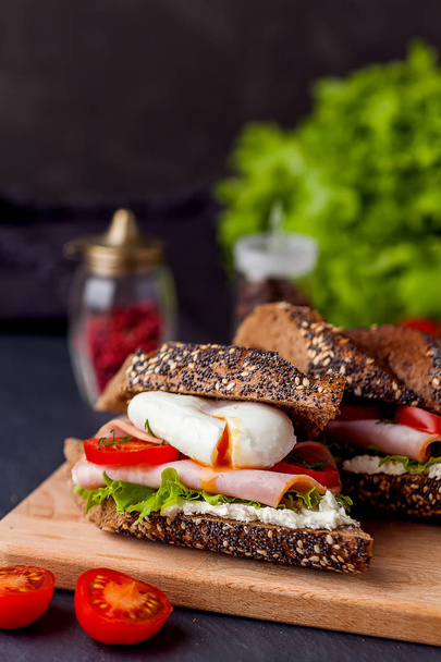 Sandwich mit Schinken und pochiertem Ei auf Holzbrett - Foto, Bild