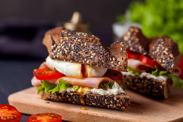 Sandwich with ham, poached egg and fresh tomatoes on wooden boar - Foto, Imagem