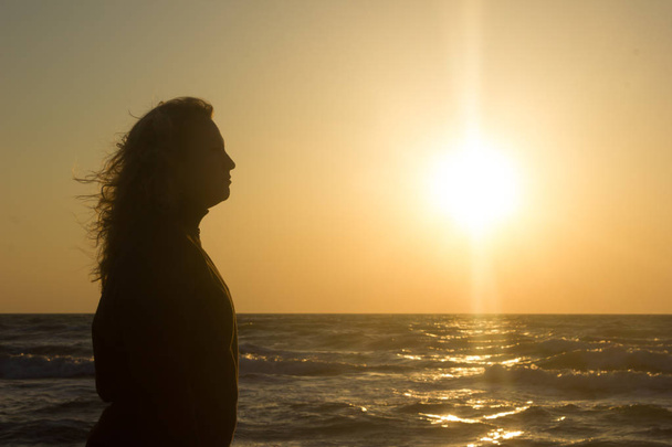 Силует дівчини на пляжі на сході сонця
 - Фото, зображення