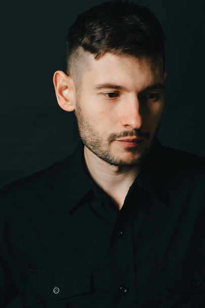 Adam kulaklık ve bir siyah arka plan üzerine siyah gömlek - Fotoğraf, Görsel