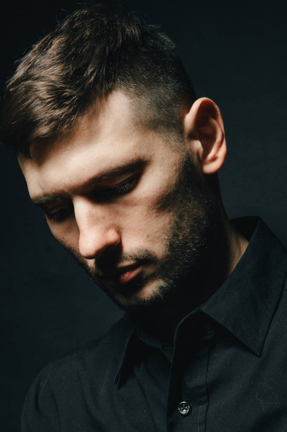 Homem em fones de ouvido e camisa preta em um fundo preto
 - Foto, Imagem