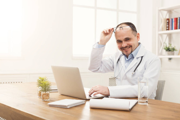 Retrato de médico en gafas sentado en el escritorio
 - Foto, Imagen