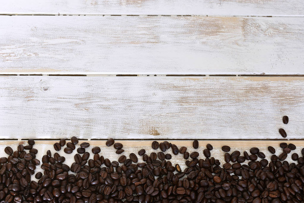 Μια αφηρημένη εικόνα του φρέσκο φρυγμένους κόκκους καφέ σε λευκό φόντο ξύλινη πλυμένο.  - Φωτογραφία, εικόνα