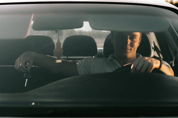 Fiatal vonzó kaukázusi Férfi ül az autóban, fehér póló - Fotó, kép