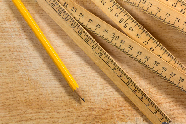 Измерительные палочки и карандаши на деревянном столе
 - Фото, изображение
