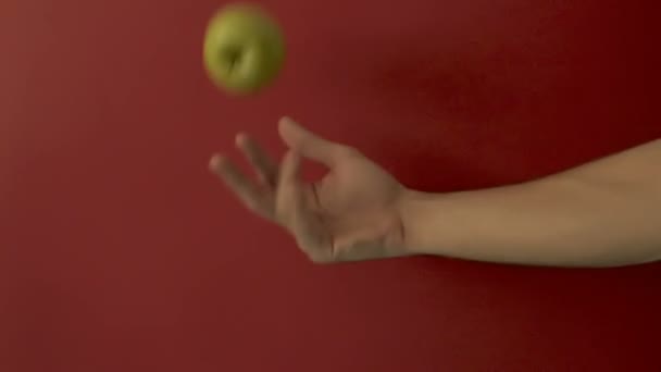 Bouncing a green apple on a red background with one hand. - Felvétel, videó