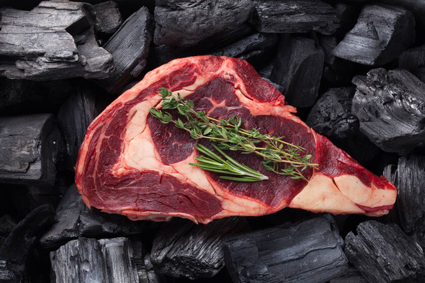 Φρέσκο ωμό κρέας Ribeye μπριζόλα στο μαύρο υπόβαθρο ξυλάνθρακα - Φωτογραφία, εικόνα