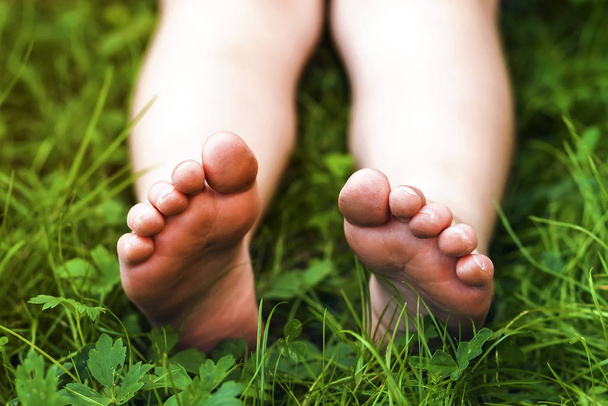 Закрыть ноги маленькой девочки на зеленой траве
 - Фото, изображение