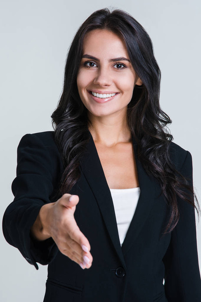 Welcome to our team! Beautiful young businesswoman greeting you and looking at camera with smile while standing against white background - Photo, Image