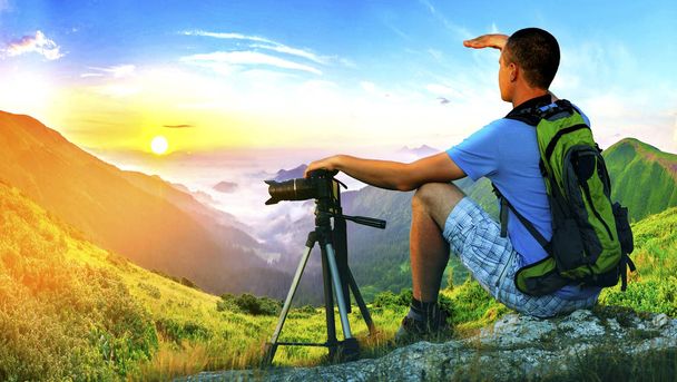 Photographe randonneur assis sur un rocher regardant vers l'avant au lever du soleil
  - Photo, image