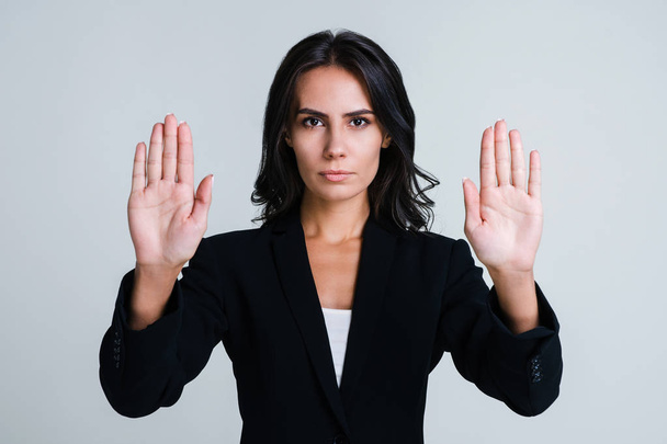 Stop! Beautiful young businesswoman looking at camera and showing her hands while standing against white background - Foto, immagini