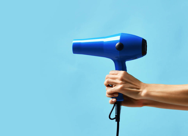 Woman hands hold blue hair dryer - Fotó, kép
