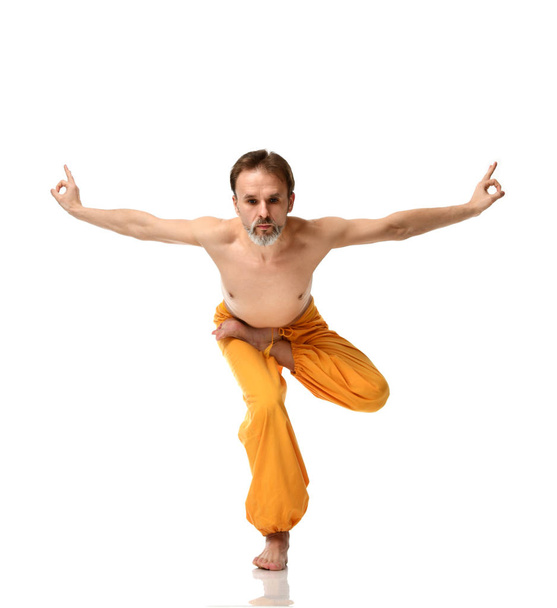 Man practicing yoga doing sport stretching exercises in yellow pants  - Valokuva, kuva
