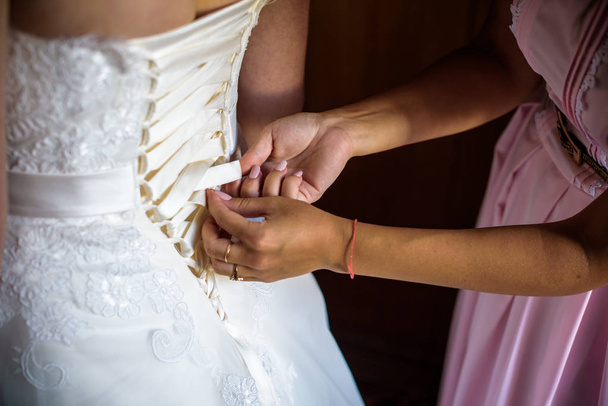 Руки крупним планом шнурки Весільна сукня корсет
 - Фото, зображення