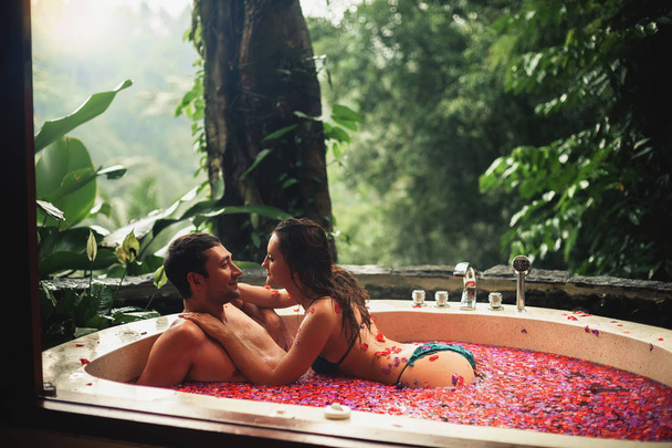 Couplere laxing bath with tropical flowers outdoor at luxury hotel - 写真・画像