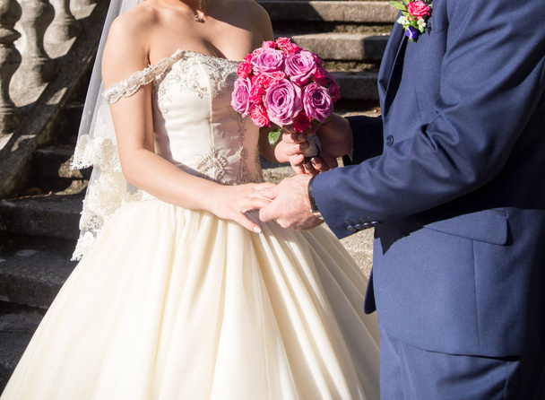 Bride and groom holding wedding bouquet with roses - Фото, изображение