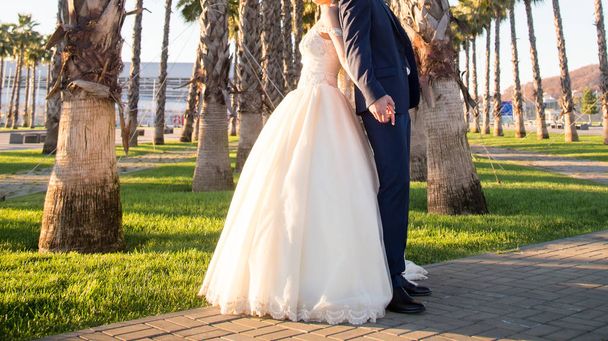 glückliche Braut und Bräutigam beim Hochzeitsspaziergang im Park - Foto, Bild