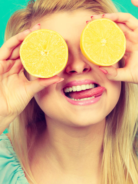 Woman holding fruit lemon half on eyes - Valokuva, kuva