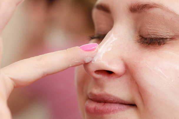 Woman applying face cream with her finger - Foto, Bild