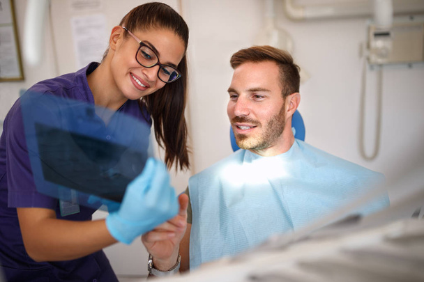 Zahnarzt mit Patient im Gespräch über zahnärztliche Röntgenaufnahmen - Foto, Bild