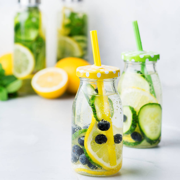 Health care, fitness, healthy nutrition diet concept. Fresh cool lemon cucumber berry infused water, cocktail, detox drink, lemonade in a glass bottle for spring summer days - Photo, Image