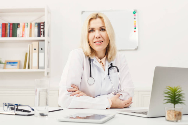 Портрет жінки-лікаря, що сидить на робочому столі
 - Фото, зображення