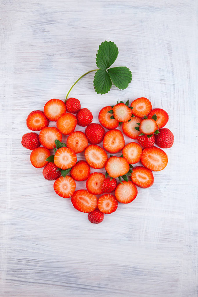fresh ripe strawberries in heart shape on white wood plate kitchen table can be used as background - Photo, image