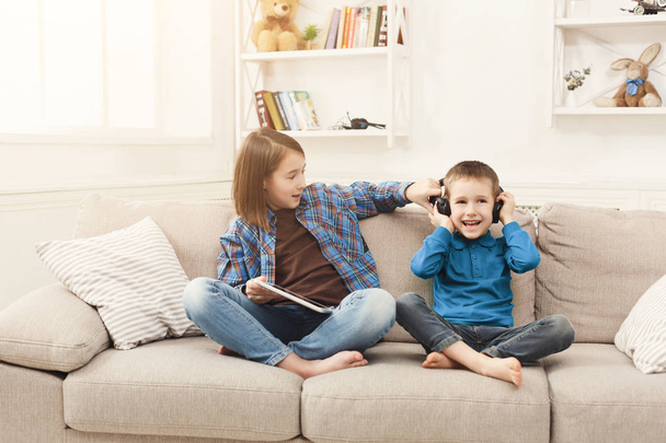 Deux enfants écoutent de la musique sur le canapé à la maison
 - Photo, image