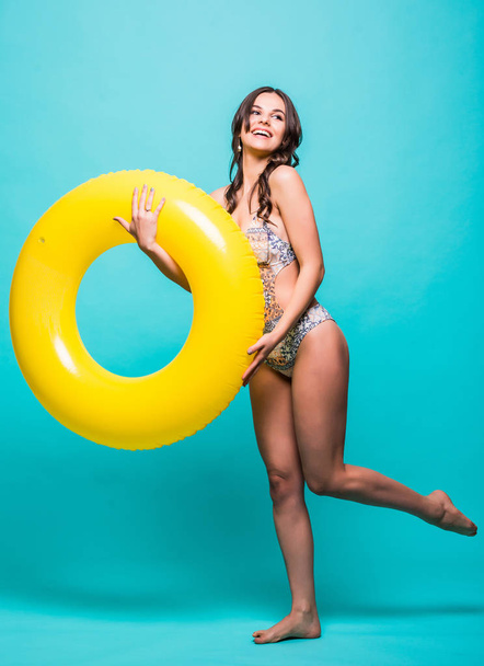 Volledige lichaam sexy vrouw in zwembroek met gele opblaasbare ring geïsoleerd op groene achtergrond - Foto, afbeelding