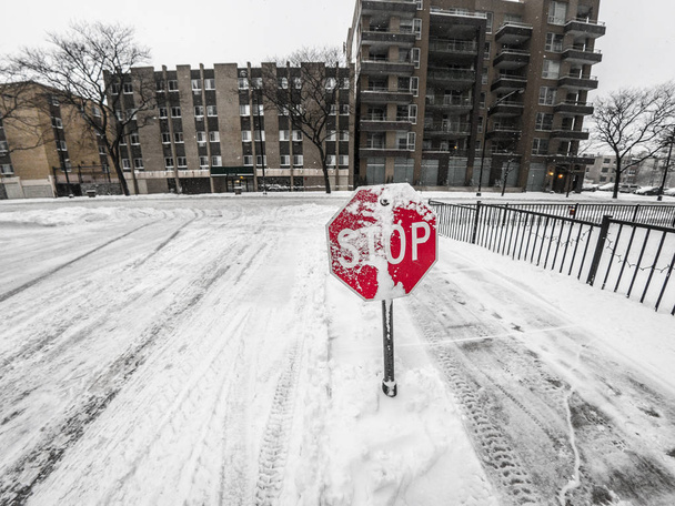 Vista de neve coberta sinal de parada vermelho com edifícios, escorregadio pá andar lado de concreto e arado rua nevada além em Chicago durante o inverno queda de neve tempo
. - Foto, Imagem