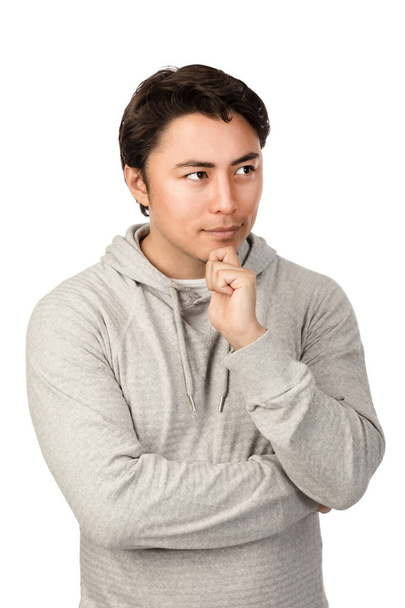 Μπερδεμένος άνθρωπος φορώντας ένα γκρι φούτερ με κουκούλα σκέψης. Στέκεται σε ένα λευκό φόντο. - Φωτογραφία, εικόνα