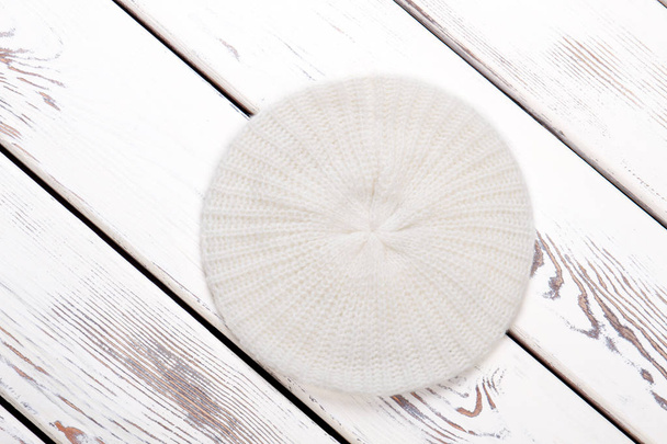White woolen beret, wooden background. - Photo, Image