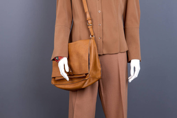 Маннекін з коричневим одягом та сумкою
. - Фото, зображення
