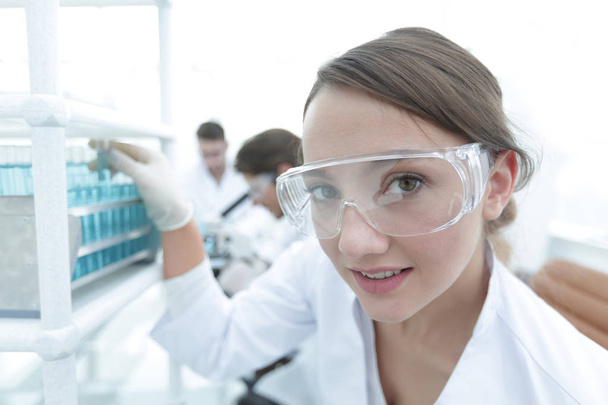 Young woman scientist in protective glasses holding test tubes - Фото, зображення