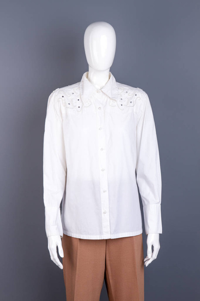Белая блузка со стразами на манекене
. - Фото, изображение
