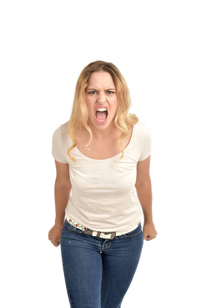 3/4 portrait of blonde girl wearing white shirt, angry expression . isolated on white background - 写真・画像