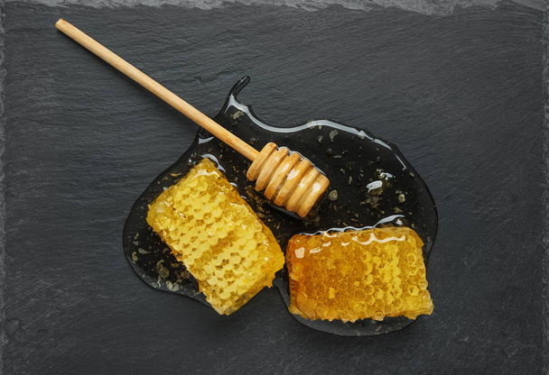 honeycomb and honey stick on a black - Foto, afbeelding
