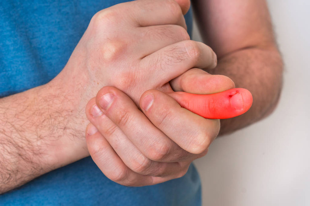 指の痛みを持つ男は、彼の痛む指を保持しています。 - 写真・画像