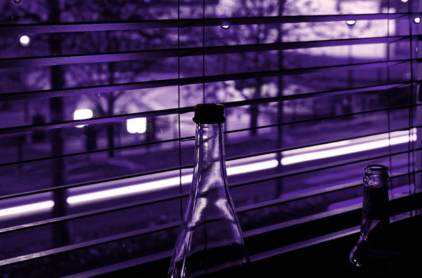 Μπουκάλια μπροστά από μια ζήλια της πόλης τη νύχτα με μοβ χρώματα με μακρά έκθεση - Φωτογραφία, εικόνα