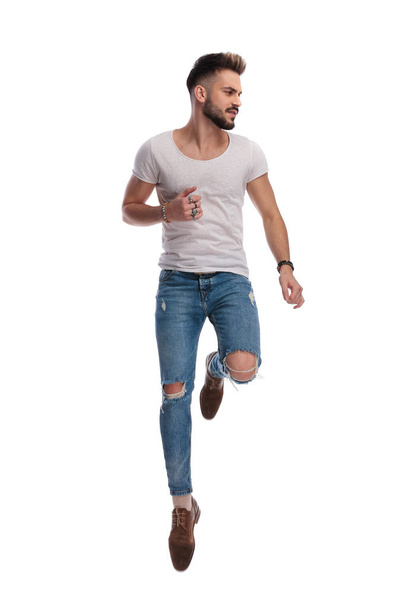 cool young casual man jumps and looks to side  - Foto, Imagen