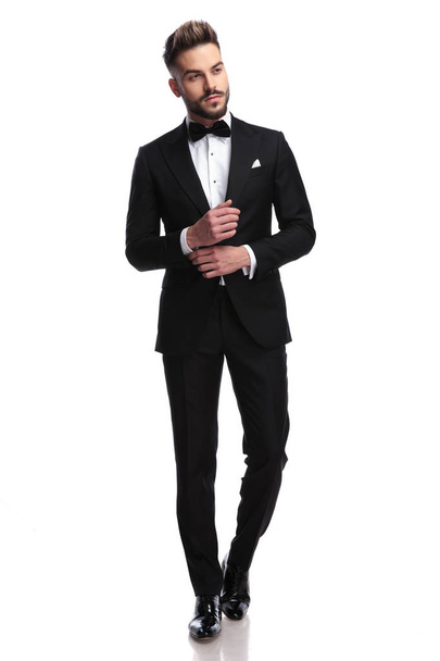 young sexy man in tuxedo and bowtie fixing his sleeve  - Photo, Image