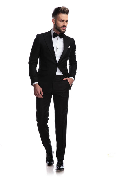 serious handsome man in tuxedo walks and looks to side - Photo, Image
