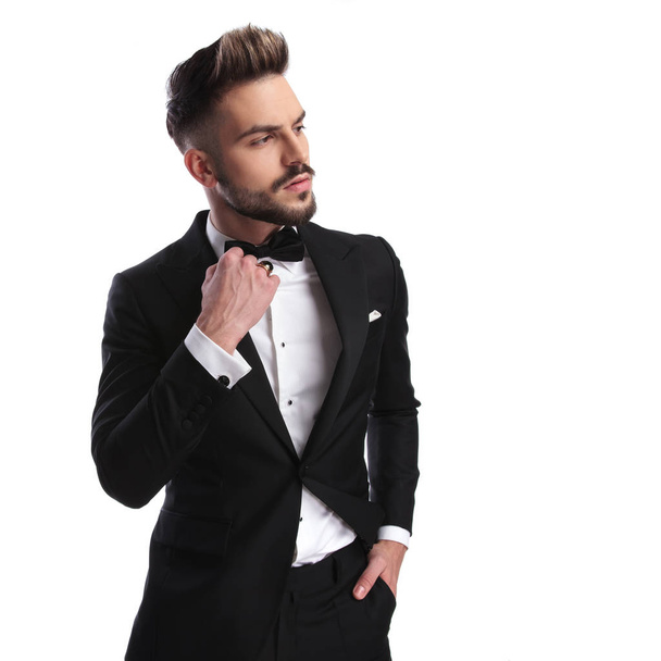 side view of a fashion model in tuxedo holding  bowtie  - Photo, Image