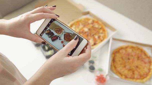 Photographie de la nourriture. Les mains prennent des photos de délicieuses pizzas et rouleaux avec un smartphone
 - Photo, image