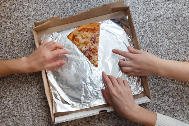 Pizza tranchée sur la table. Les mains de trois humains sont prises pour un dernier morceau sur la table
. - Photo, image