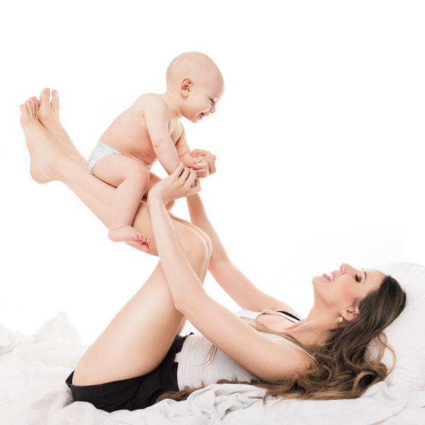Happy mother lifting her adorable baby son in the air. Happy family. Mother and newborn child portrait isolated on white background. - Fotografie, Obrázek