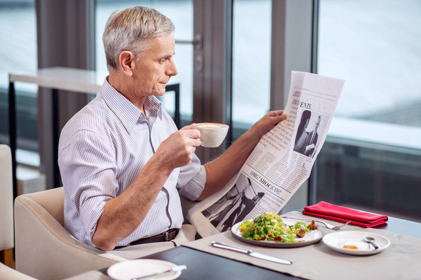 Concentrated mature man finishing breakfast - Photo, Image